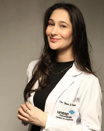 Dra. Bianca Rafaeli Piovezan de jaleco branco, com o emblema da UNESP Odontologia.